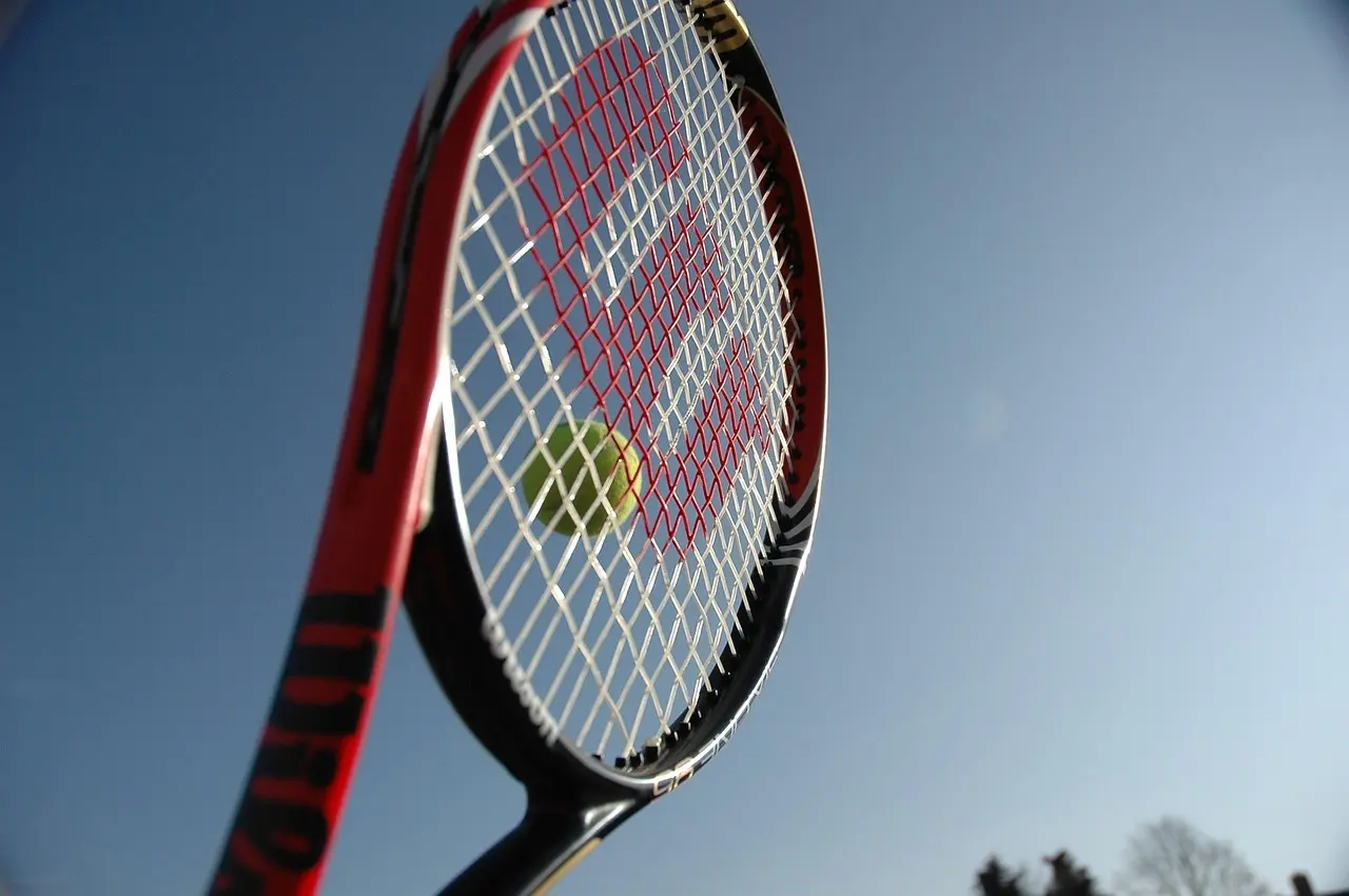 Tennisketcher med tennisbold mod blå himmel